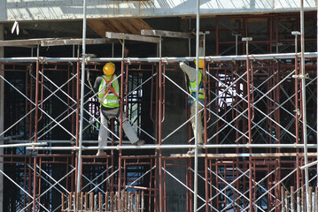 Wall Mural - PERAK, MALAYSIA -APRIL 05, 2016: Construction workers wearing safety harness and installing scaffolding at high level in the construction site. 
