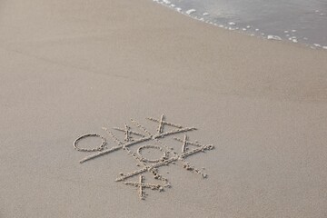 Canvas Print - Tic tac toe game drawn on sand near sea, space for text