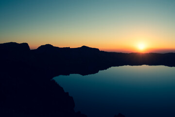 Wall Mural - Sunset over Crater Lake National Park in Oregon, with the rim of the Crater in silhouette. 