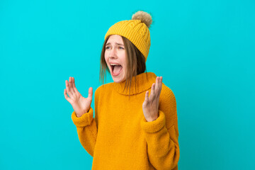 Young English woman wearing winter jacket isolated on blue background with surprise facial expression