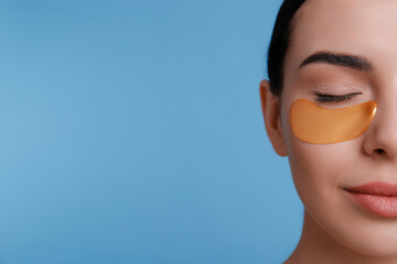 beautiful young woman with under eye patch on light blue background, closeup. space for text
