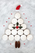 Surreal Christmas Tree Mince Pies Concept Shape,with Santa Hat Decoration, Pine Cones And Winter Holly With Red Berries On Snow Background. Festive Food Design For Xmas And New Year.