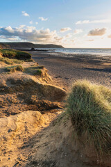 Wall Mural - Stunning Summer sunset landscape image of Widemouth Bay in Devon England with golden hour light on beach