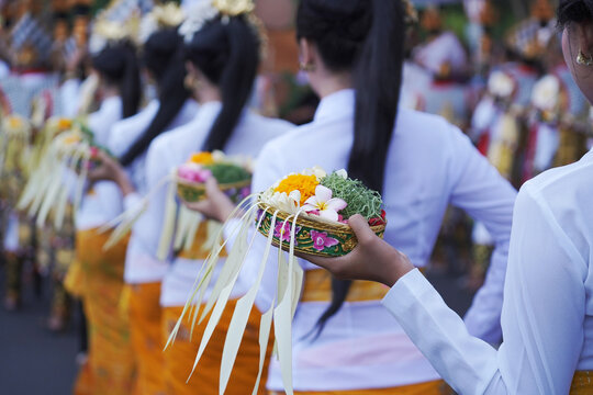 Group of women in traditional Balinese costumes carry religious offering for hindu ceremony on street parade at art and culture festival.