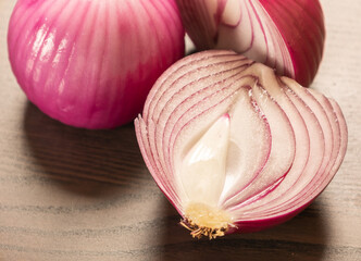 Wall Mural - two red onions close up on wooden background