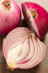 Wall Mural - two red onions close up on wooden background