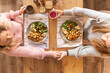 © Austockphoto - Top down shot of two women  holding hands across the dinner table