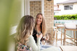 © Austockphoto - Two smiling women sitting outside looking at eachother while holding a champagne glass