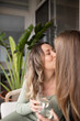 © Austockphoto - Two women kissing outside while holding glasses of wine