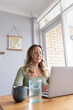 © Austockphoto - Woman wearing green sweater with eyeglasses working on laptop at kitchen table