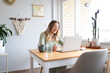 © Austockphoto - Smiling woman with green sweater sitting down looking at a laptop on the table