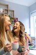 © Austockphoto - Laughing female same sex couple standing together with coffees in their kitchen