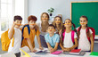 © Studio Romantic - Funny photo of schoolchildren and teacher keeping pencils between nose and mouth in class and looking at camera at elementary school. Cheerful school life concept. Modern education in primary school.