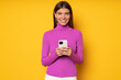 © Damir Khabirov - Smiling young woman holding phone, isolated on yellow background