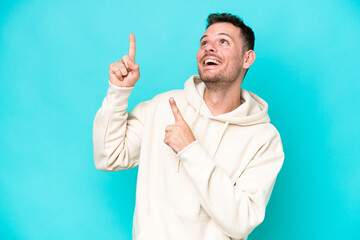 Wall Mural - Young caucasian handsome man isolated on blue background pointing with the index finger a great idea