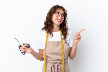 Wall Mural - Young caucasian seamstress woman isolated on white background pointing up a great idea