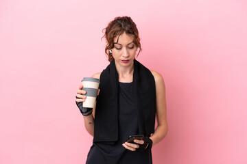 Wall Mural - Sport sport woman with towel isolated on pink background holding coffee to take away and a mobile