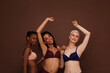 © Artem Varnitsin - Three women in lingerie are laughing. Females in underwear dancing against a brown backdrop.