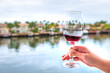 Woman person hand holding, toasting with wineglass glass of French red wine Cotes Du Rhone on luxury house home waterfront balcony in Miami, Florida