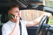 © Евгений Шемякин - Handsome young man driving car and talk on cell mobile phone, driver in automobile use smartphone