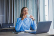© DSMT - Portrait of cheerful woman in classic glasses smiling in free time in cafe with coffee, positive european woman in blue shirt, desk with laptop, remote work