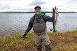 © Mat Hayward - Happy and proud fisherman holding bloody Coho salmon fish on riverbank in Alaska