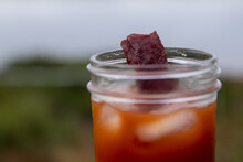 Bloody Mary Vodka Drink In A Glass Jar With Ice, Tomato Juice And A Beef Jerky Garnish