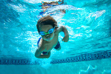 Underwater Young Boy Fun In The Swimming Pool With Goggles. Summer Vacation Fun.
