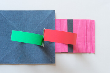 Poster - green and red paper stripes looped and held in place with a clip on gray blue and pink paper background