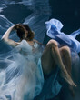 © Pavel Karchevskii - fashionable girl in a beautiful white dress under water in blue light and fluttering fabric in the depths