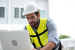 © Montri - CAucasian Man Worker in a construction site. Architecture engineering holding a laptop on building site checking plans. Successful engineer or architect, Joyous businessman. Construction worker.