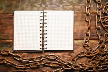 Wall Mural - open blank page notebook with copy space and old rusty iron chain on the wooden table background. to