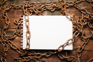 Wall Mural - open blank page notebook with copy space and old rusty iron chain on the wooden table background. to