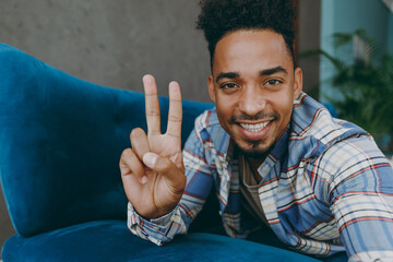 Sticker - Close up young man in casual shirt lay down on blue sofa do selfie shot pov on mobile cell phone show v-sign stay at home rest relax spend free spare time in living room indoor People lounge concept