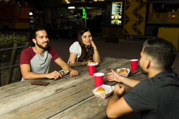 Wall Mural - Mexican friends having fun eating from the food cart