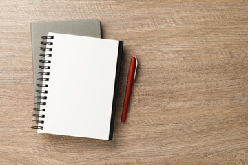 Notebooks and pen on wooden table, flat lay. Space for text