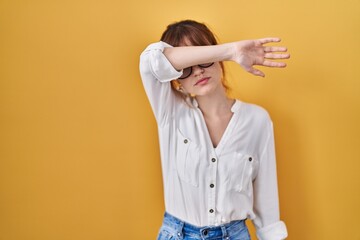 Poster - Young beautiful woman wearing casual shirt over yellow background covering eyes with arm, looking serious and sad. sightless, hiding and rejection concept