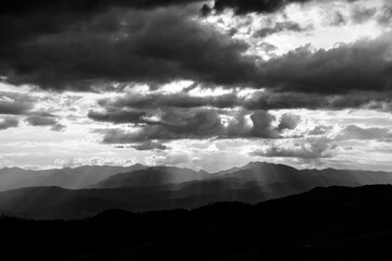 Wall Mural - black and white mountain view. fog is covering the valley, sunset sky is illuminating the ridge of t