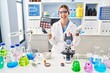 © Krakenimages.com - Young blonde woman working at scientist laboratory with make up celebrating achievement with happy smile and winner expression with raised hand