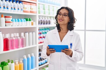 Canvas Print - Young beautiful hispanic woman pharmacist using touchpad working at pharmacy