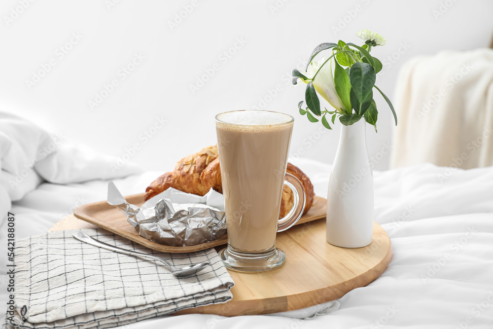Tray with tasty breakfast and coffee on white blanket in bedroom