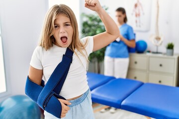 Poster - Blonde little girl wearing arm on sling at rehabilitation clinic annoyed and frustrated shouting with anger, yelling crazy with anger and hand raised