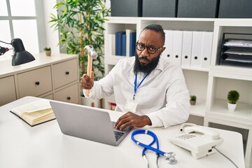 Sticker - African american man working at medical clinic holding hammer thinking attitude and sober expression looking self confident