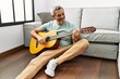 © Krakenimages.com - Middle age grey-haired man playing classical guitar sitting on floor at home