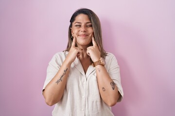 Wall Mural - Blonde woman standing over pink background smiling with open mouth, fingers pointing and forcing cheerful smile