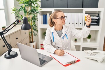 Canvas Print - Young blonde woman wearing doctor uniform prescribe pills at clinic