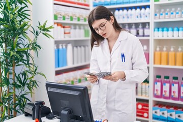 Sticker - Young caucasian woman pharmacist smiling confident counting dollars at pharmacy