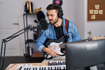 Canvas Print - Young hispanic man singing song playing electric guitar at music studio