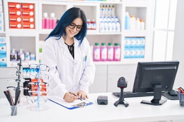 Wall Mural - Young caucasian woman pharmacist smiling confident writing on document at pharmacy