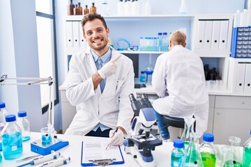 Poster - Hispanic man and woman working at scientist laboratory smiling happy pointing with hand and finger to the side